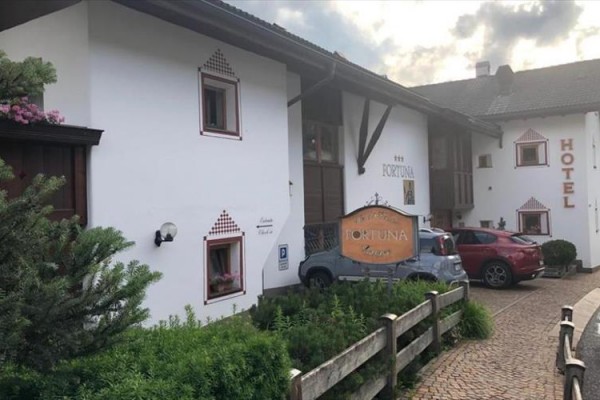 Budova hotela s parkoviskom a nápisom 