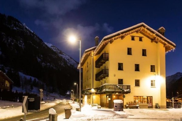 Snehom pokrytý horský hotel osvetlený pouličnou lampou v noci.