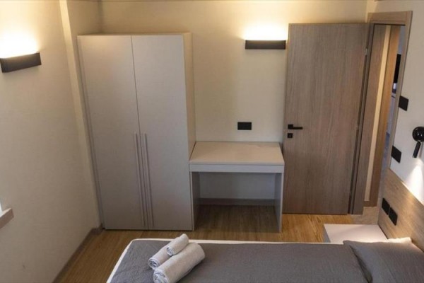 Moderná spálňa so šatníkovou skriňou, posteľou a poskladanými uterákmi na posteli.